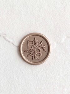 Sello de lacre Champagne con iniciales sobre papel artesanal blanco