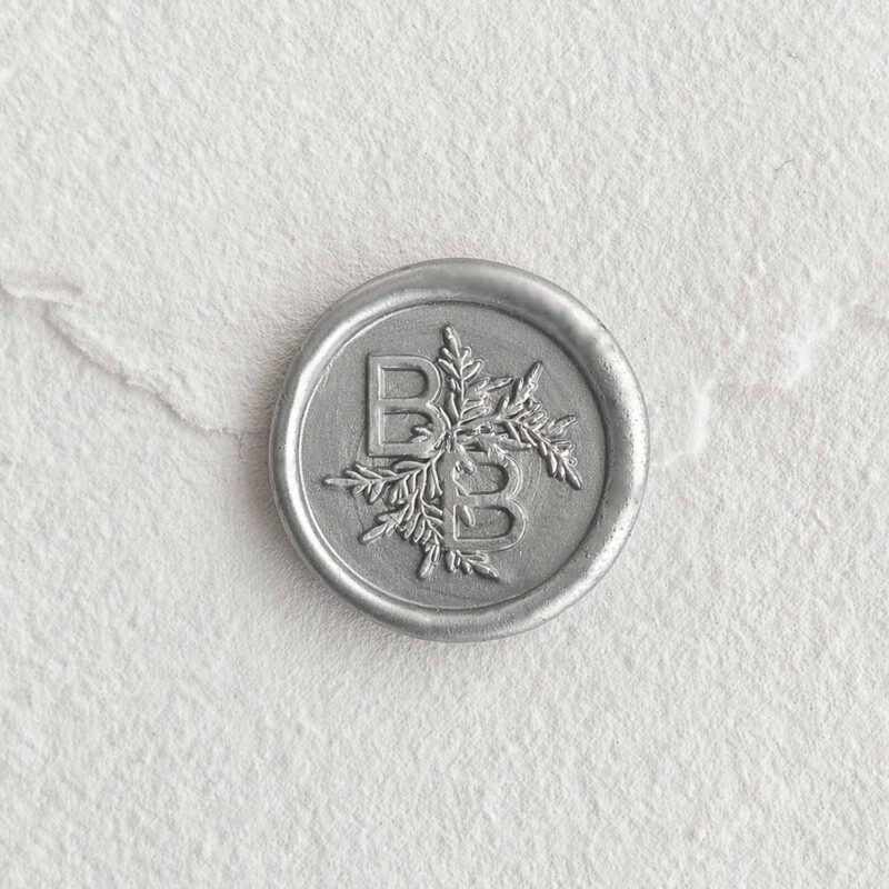 Sello de lacre Plata con iniciales sobre papel artesanal blanco
