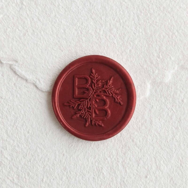 Sello de lacre Burdeos Perlado con iniciales sobre papel artesanal blanco