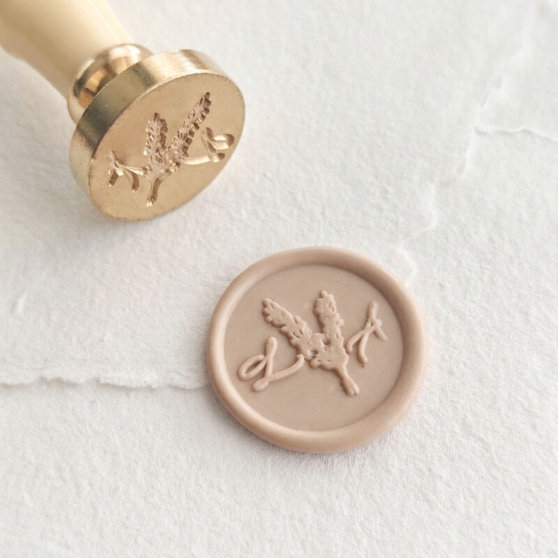 Detalle de sello de lacre personalizado con iniciales y ramas silvestres