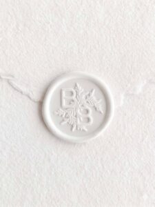 Sello de lacre Blanco Mate con iniciales sobre papel artesanal blanco