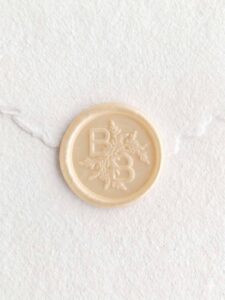 Sello de lacre Marfil Perla con iniciales sobre papel artesanal blanco