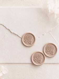 Sello de lacre adhesivo con diseño de hortensia en relieve sobre sobre artesanal para invitaciones de boda románticas y elegantes.