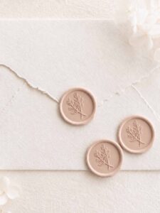 Sello de lacre adhesivo con diseño clásico de ramas cruzadas sobre sobre artesanal para invitaciones de boda elegantes.