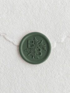 Sello de lacre Secuoya con iniciales sobre papel artesanal blanco