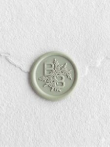 Sello de lacre verde Suculenta con iniciales sobre papel artesanal blanco