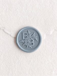 Sello de lacre Bruma Marina con iniciales sobre papel artesanal blanco