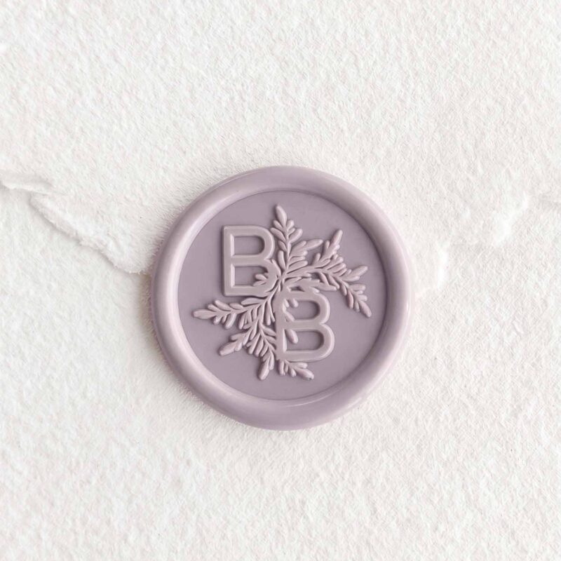 Sello de lacre Gris lavanda con iniciales sobre papel artesanal blanco