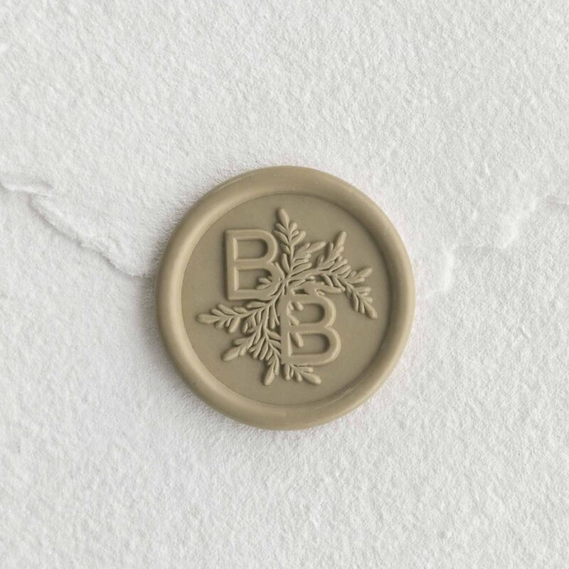 Sello de lacre Oliva con iniciales sobre papel artesanal blanco