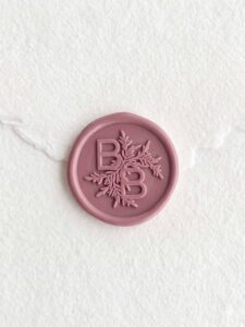 Sello de lacre Rosa Dalia con iniciales sobre papel artesanal blanco