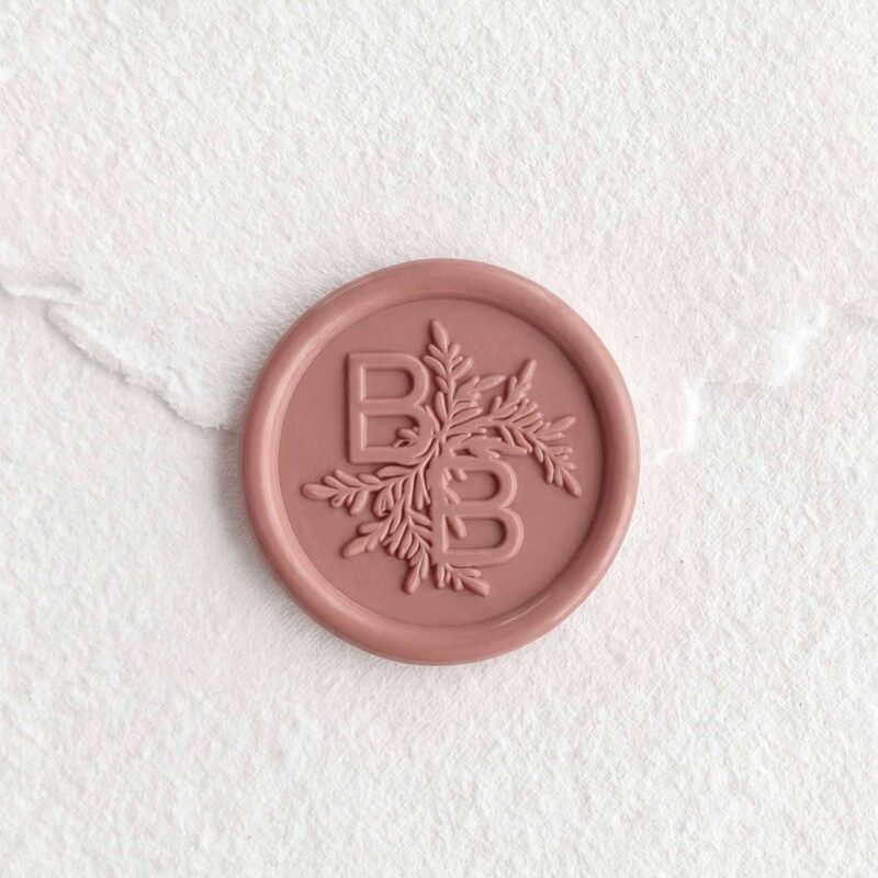 Sello de lacre Rosa Tierra con iniciales sobre papel artesanal blanco