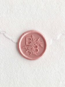 Sello de lacre Rose Perla con iniciales sobre papel artesanal blanco