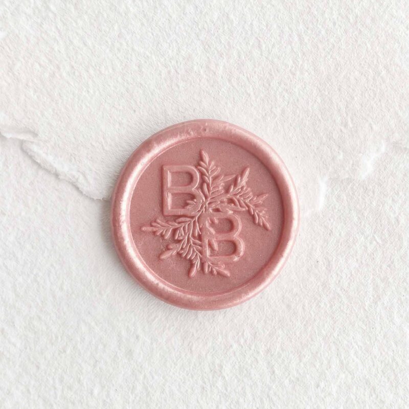 Sello de lacre Rose Perla con iniciales sobre papel artesanal blanco