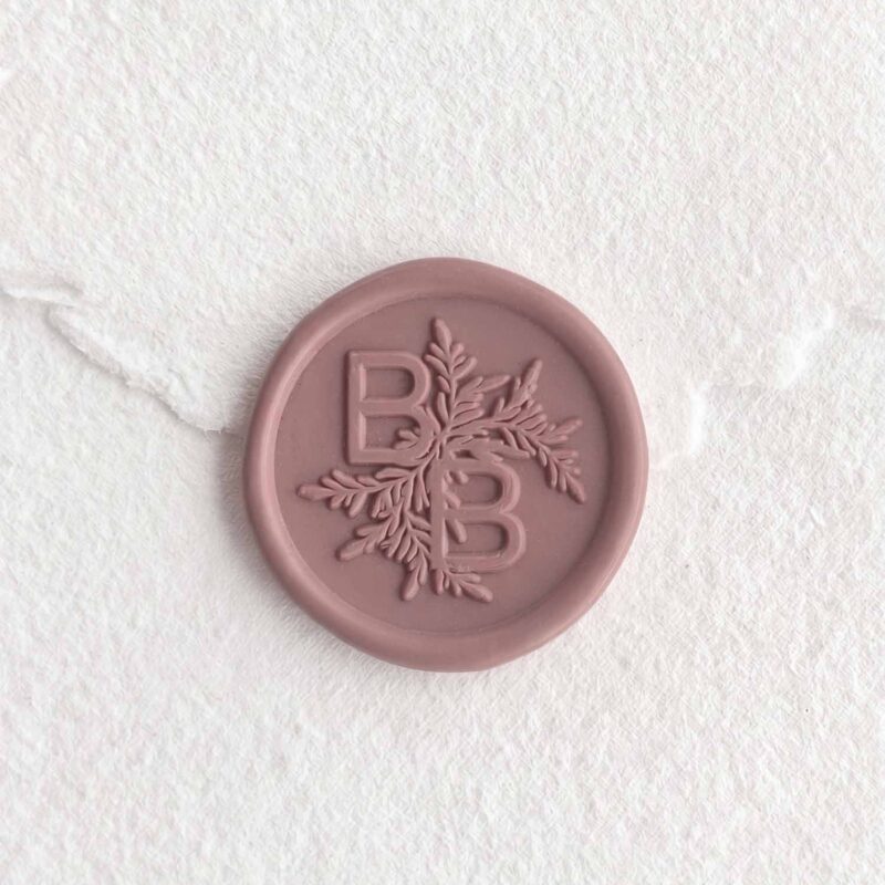 Sello de lacre Tierra Malva con iniciales sobre papel artesanal blanco