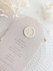 Sigillo in ceralacca adesivo personalizzato in stile botanico applicato su un menù di matrimonio in carta artigianale.