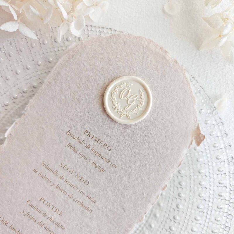 Sigillo in ceralacca adesivo personalizzato in stile classico con iniziali all’interno di una ghirlanda, applicato su un menù di matrimonio. Ideale per mantenere un’immagine coordinata in tutta la stationery dell’evento.