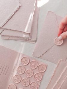 Sobre rosa de papel artesanal cerrado con sello de lacre adhesivo floral