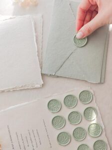 Sobre verde de papel artesanal cerrado con sello de lacre adhesivo botánico