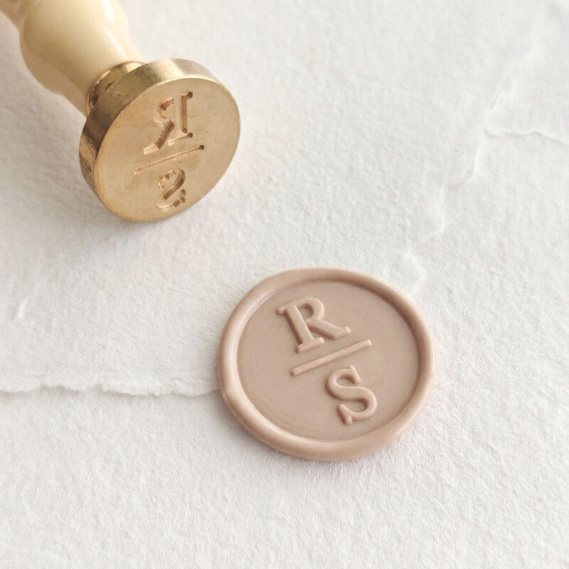 Detalle de sello de lacre personalizado con iniciales minimalistas y línea divisoria