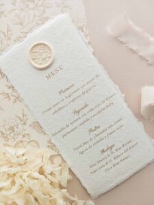 Menú de boda Adriana en papel artesanal marfil con sello de lacre botánico e impresión beige.