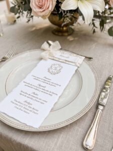 Menú de boda Adriana en papel artesanal marfil con puesto de mesa personalizado y cinta de seda marfil.