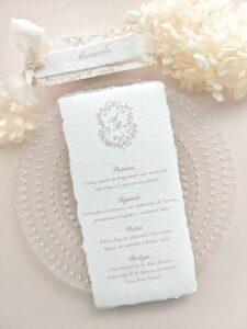 Papelería de mesa Adriana con menú de boda en papel artesanal y puesto de mesa personalizado en tonos beige.