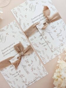 Papelería de mesa Gadea con menú de boda, puesto de mesa y cinta de seda en tonos tierra.