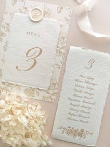 Seating plan y número de mesa Adriana en papel artesanal marfil con estampado floral beige y lacre personalizado.
