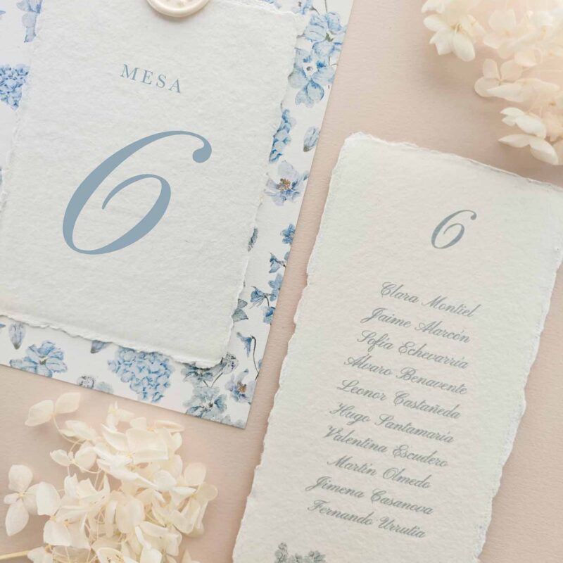 Seating plan y número de mesa Chloé en papel artesanal marfil con estampado floral azul y lacre.
